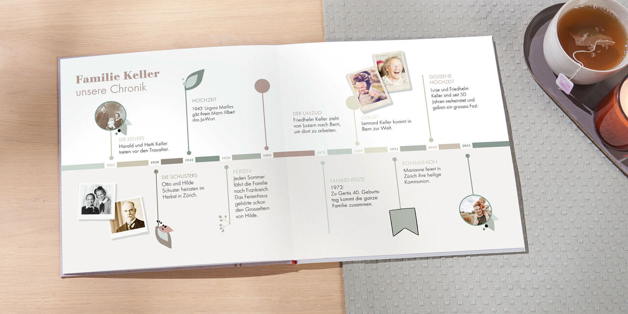 Auf dem Tisch liegt ein offenes CEWE FOTOBUCH. Zu sehen ist eine bunte Zeitleiste einer Familie von 1921 bis 2021. Sie erstreckt sich über eine Doppelseite und ist mit einigen kleinen Fotos verziert. Neben dem Fotobuch steht ein schmales Tablett mit einer Tasse Tee und einer leuchtenden Kerze.